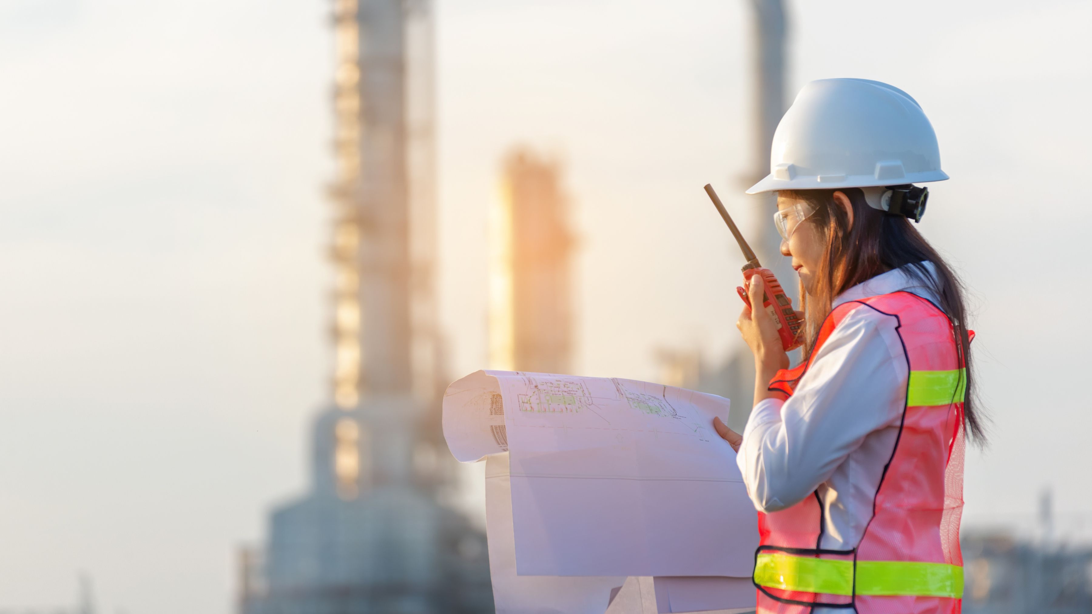 female engineer reviewing drawings in front of a renewable energy plant