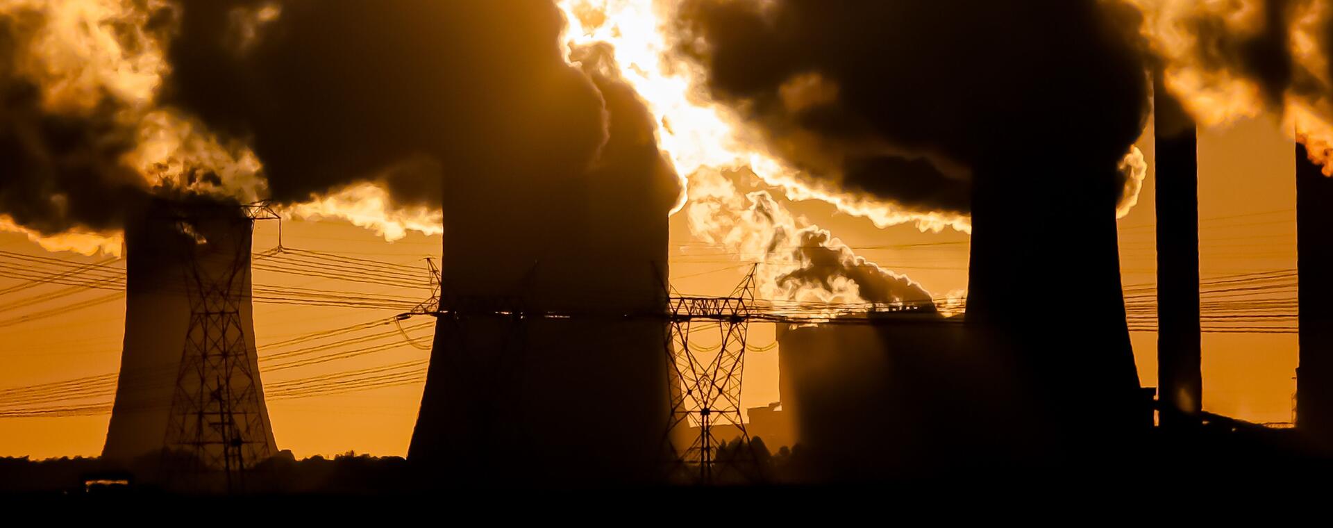 coal power plant with smoke against orange sunset